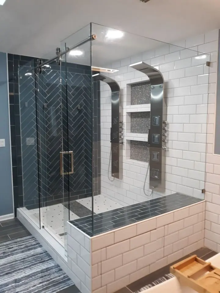 Frameless shower enclosure with a herringbone tile wall